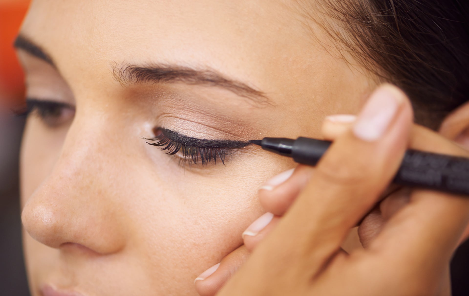 Woman applying NYX liquid eyeliner creating winged cat eye look